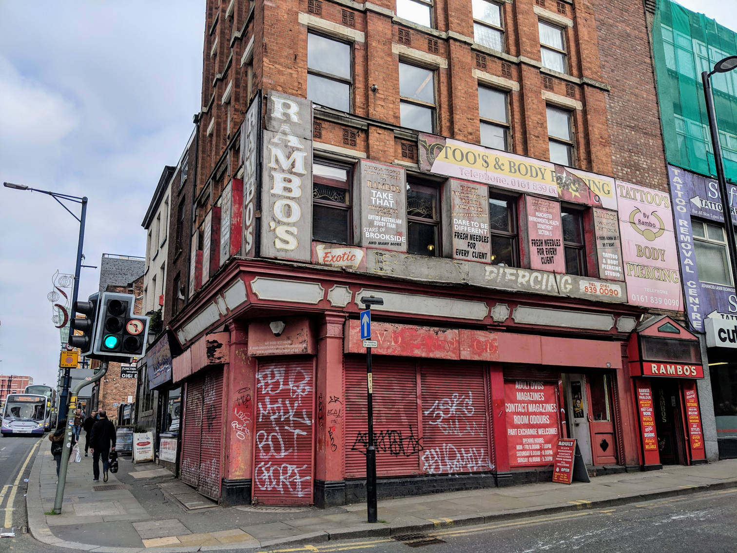 Dilapidated tattoo parlour with many ghost signs