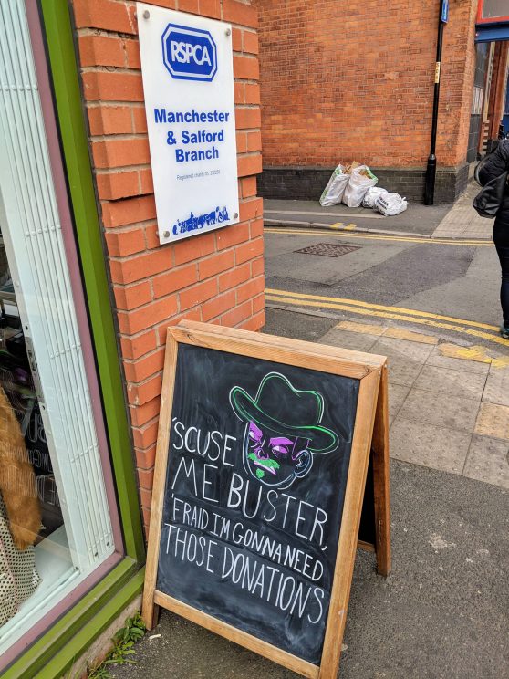 A-board outside a charity shop: "'Scuse me buster, 'fraid I'm gonna need those donations"