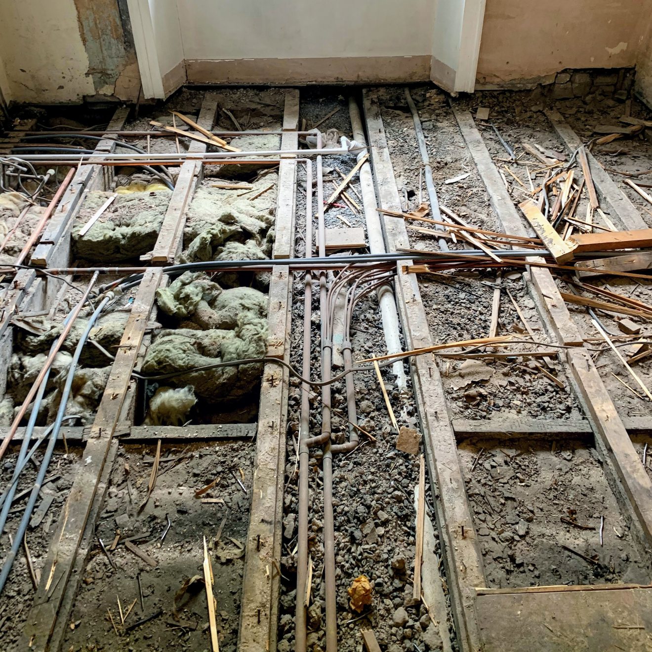 A floor without the floorboards, with deafening and pipes visible