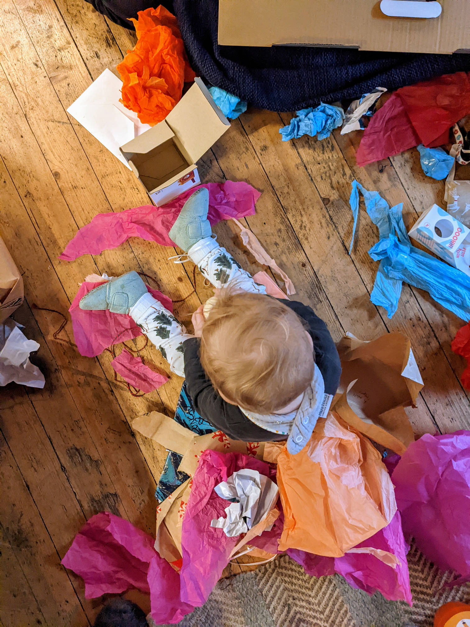 Izzy surrounded by tissue paper from opened Christmas presents