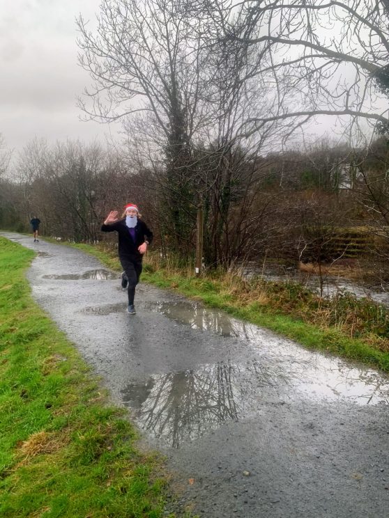 Me wearing a Santa hat and beard, running through puddles